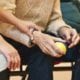 caregiver assisting an old man to hold a ball