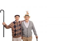 elderly man doing a peace sign on the head of another old man